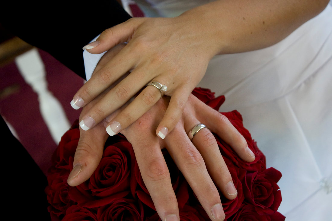 Showing off wedding rings over the bouquet