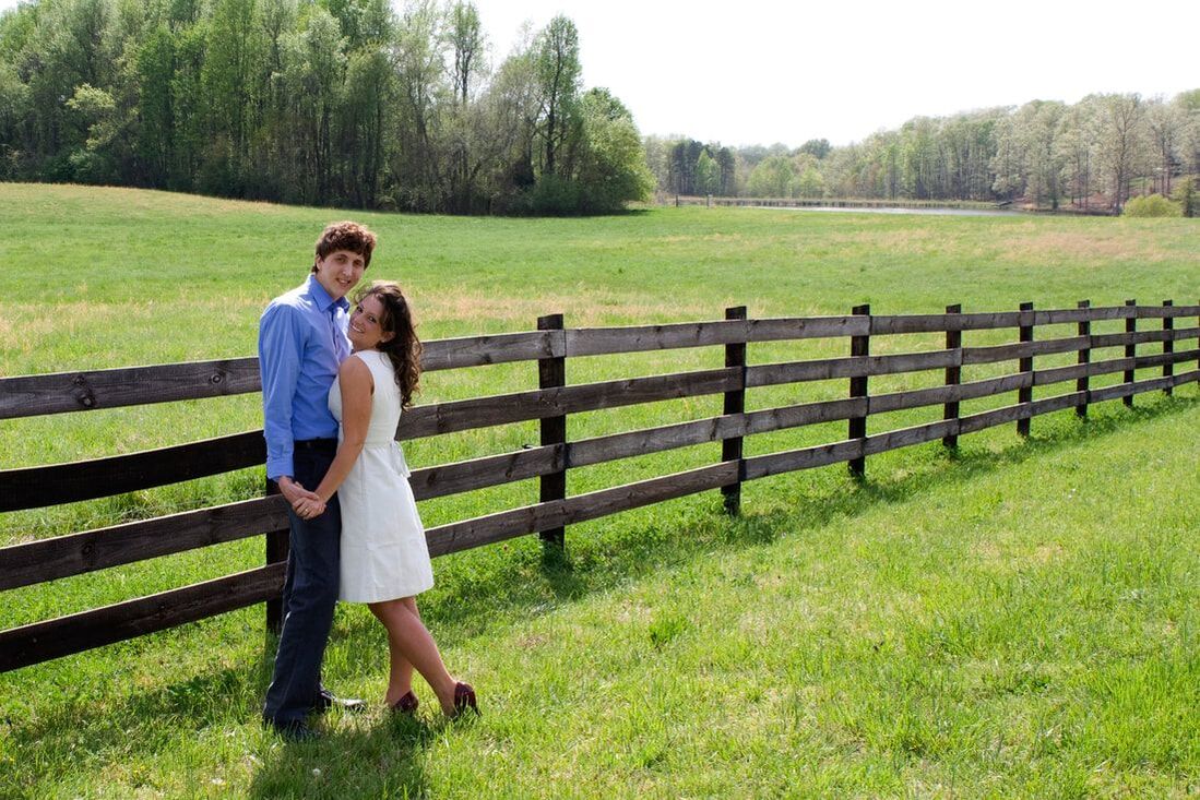Engaged couple standing by wooden fence