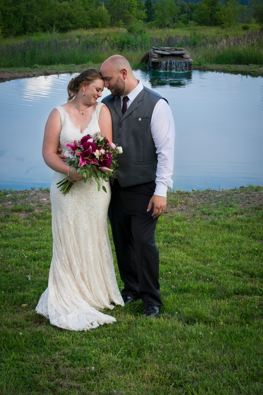 Bride and groom standing in front of small pond